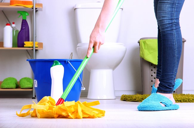Pessoa limpando o banheiro com esfregão
