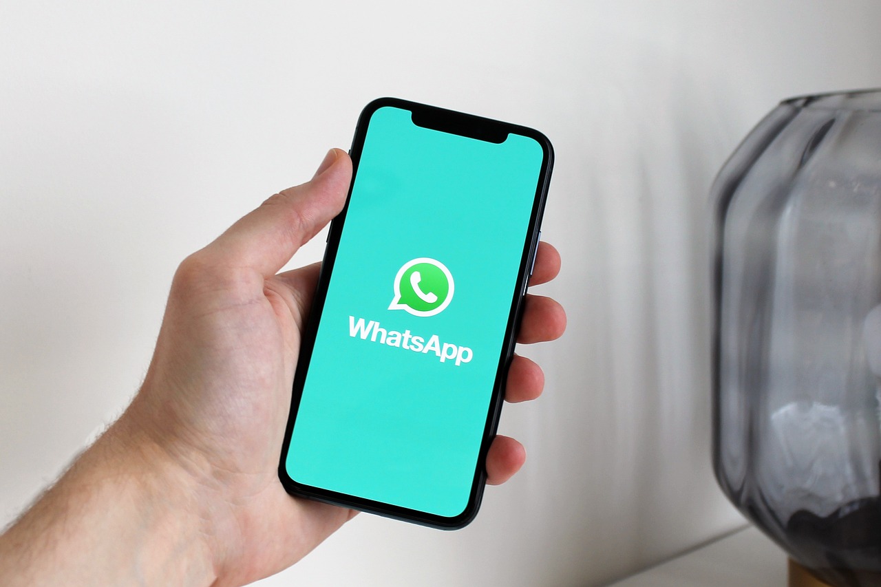 Mão segurando celular com tela mostrando a logo do WhatsApp.
