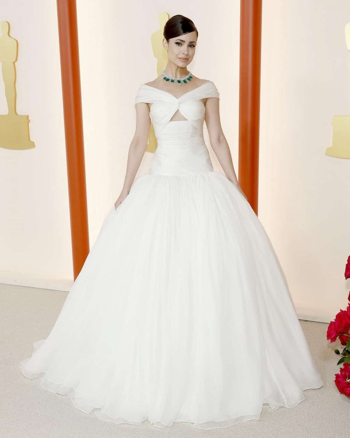 Sofia Carson no Oscar 2023 com seu vestido branco feito por Giambattista Valli, e seu colar extravagante da Chopard.